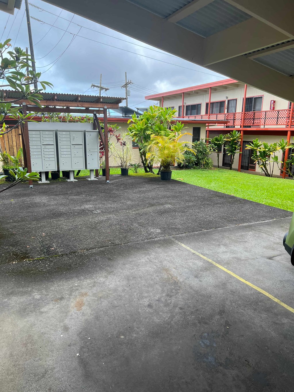 a driveway in front of a building with plants and a sign