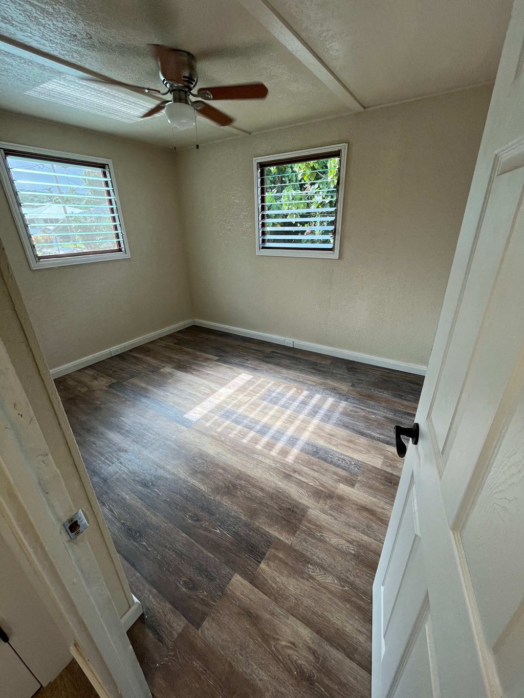 an empty room with a ceiling fan and wood floors