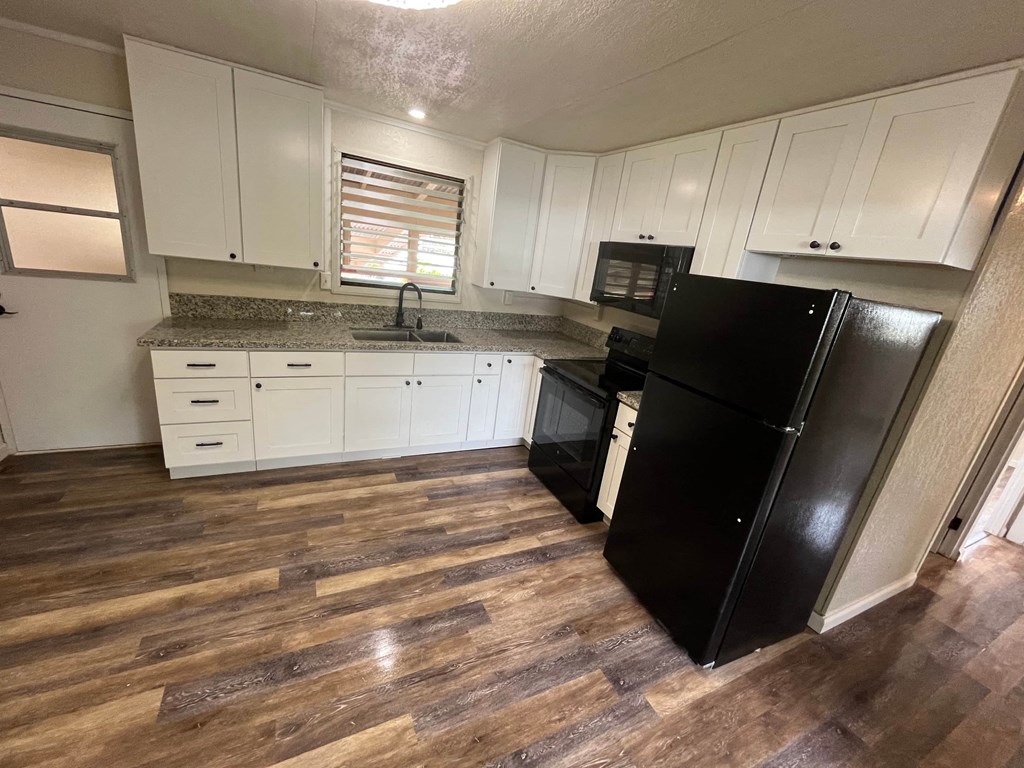 a kitchen with white cabinets and a black refrigerator