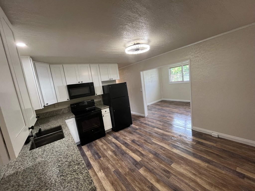 an open living room with a kitchen with a stove and refrigerator