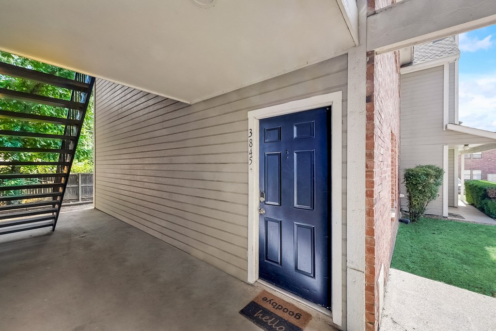 the front door of a home with a blue door opening to a porch