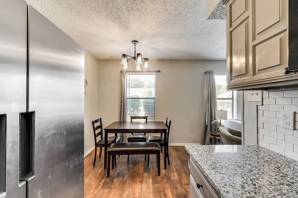 the kitchen and dining area of a home with a table and chairs