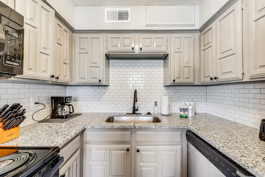 a kitchen with white cabinets and granite counter tops and a sink