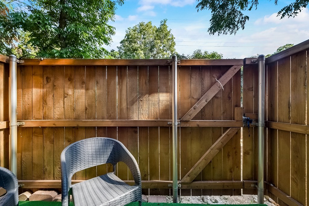 a backyard with a wooden fence and a patio with a chair
