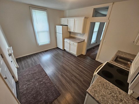A kitchen with a refrigerator, oven, and cabinets.