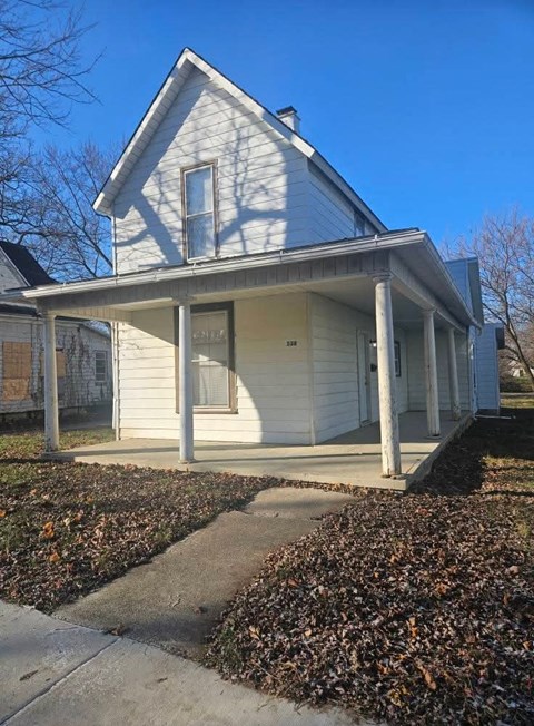 A small white house with a porch and a covered walkway.