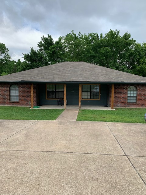 A small house with a grey roof and a green lawn in front.
