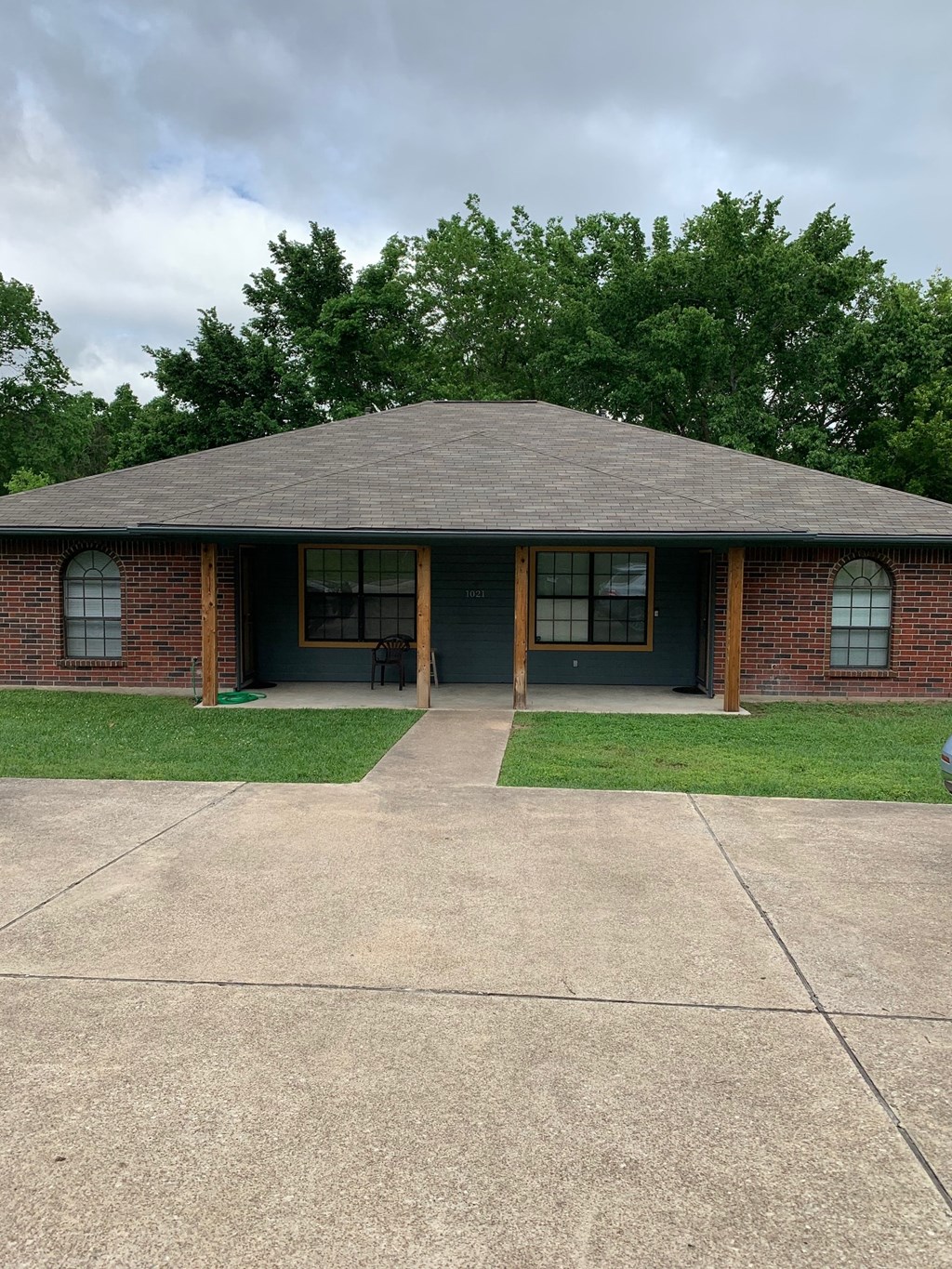 A small house with a grey roof and a green lawn in front.