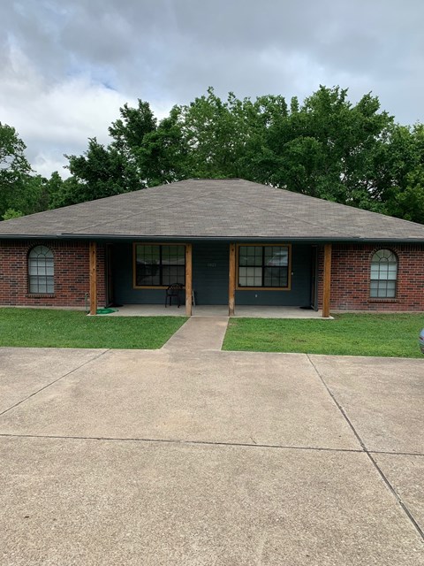 A small house with a grey roof and a green lawn in front.