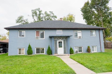 a blue house with a lawn and a sidewalk