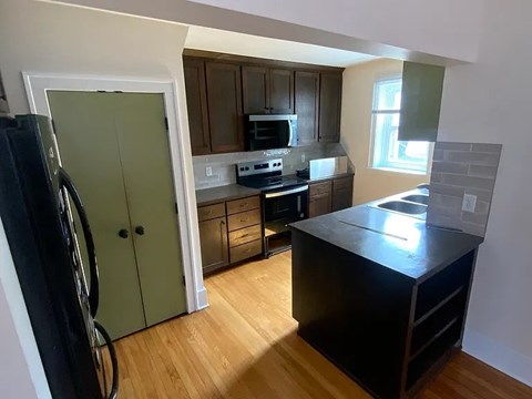 A kitchen with a black counter top and wooden floors.