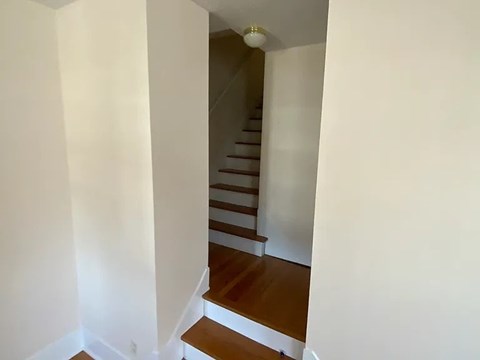 A staircase with wooden steps and a white wall.