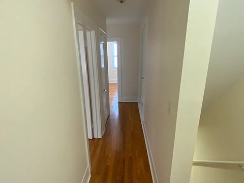 A long hallway with wood floors and white walls.