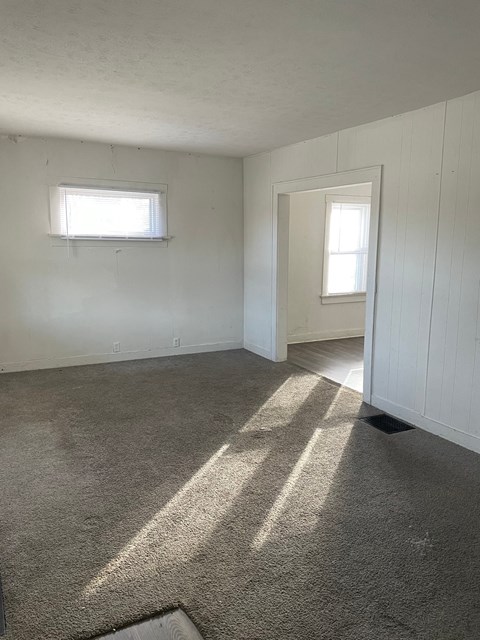an empty living room with carpet and a window