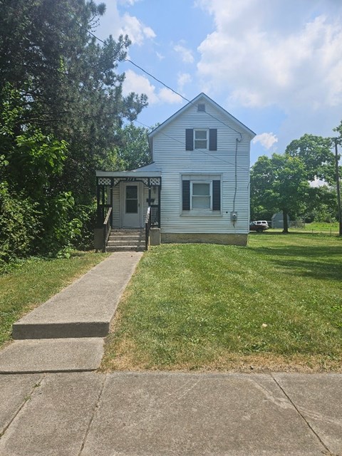 a small white house with a sidewalk in front of it