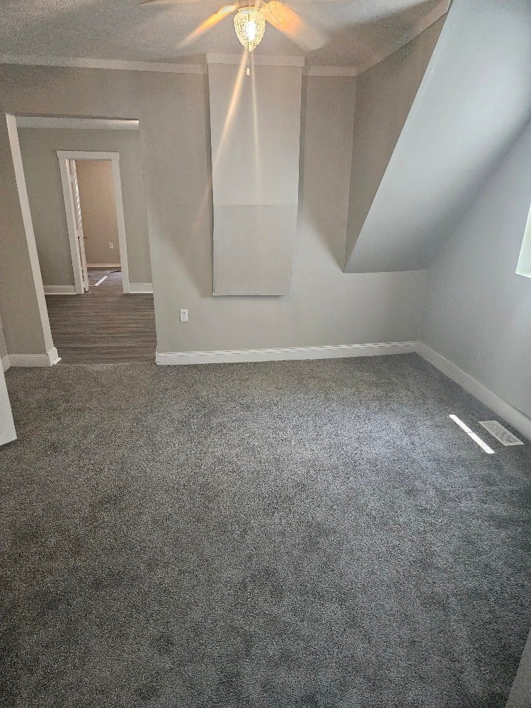 a empty room with a carpeted floor and a ceiling fan