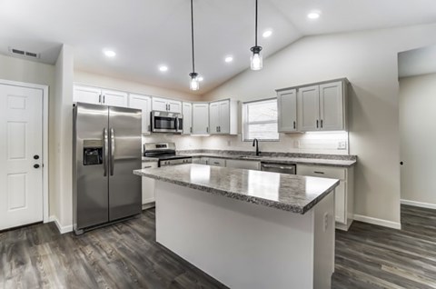 A modern kitchen with a large island and stainless steel appliances.