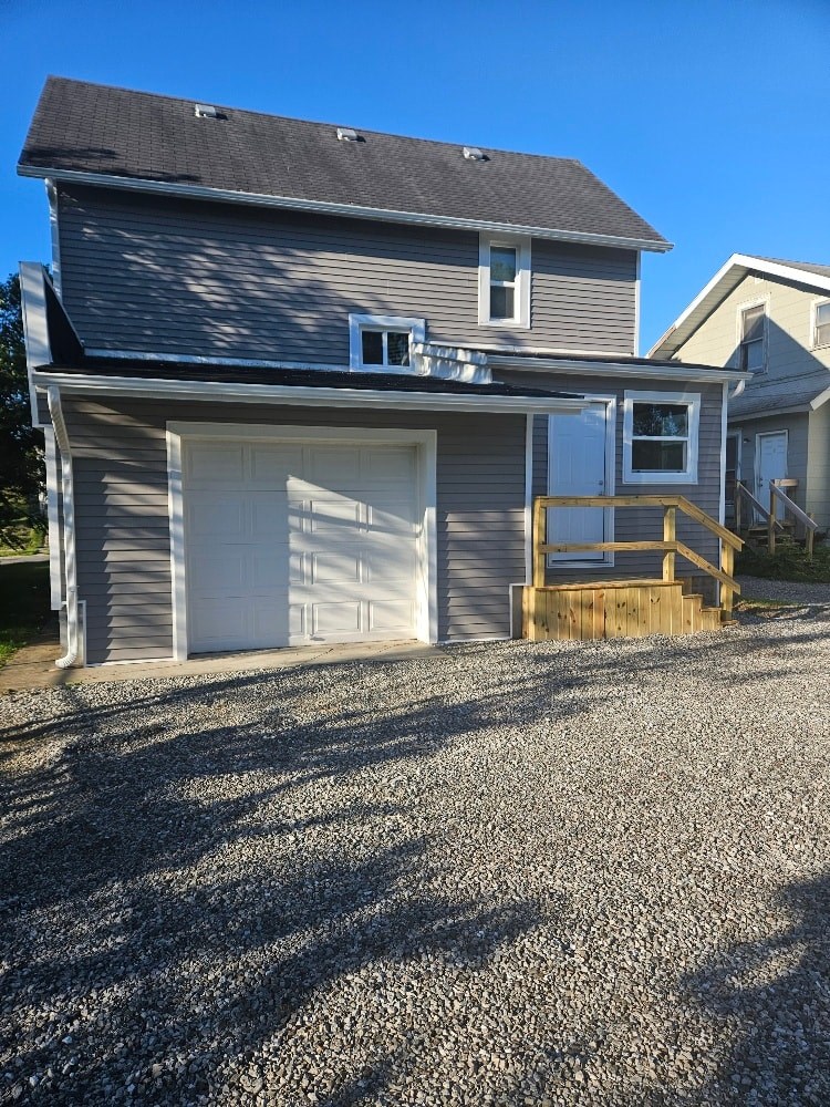 A house with a grey garage door and a brown deck.