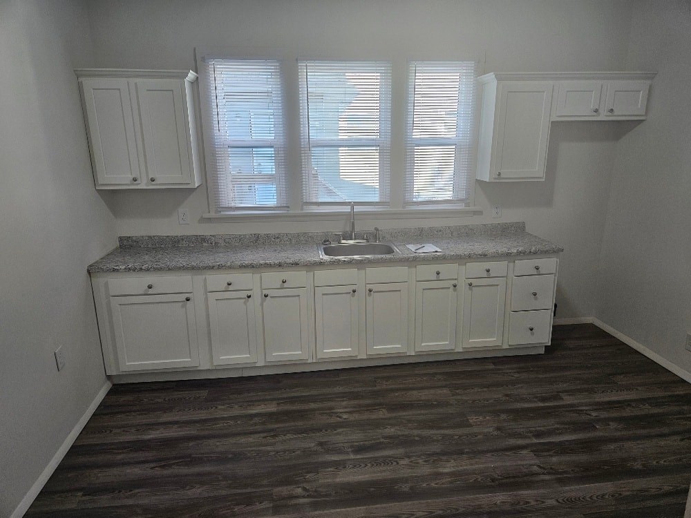 A kitchen with white cabinets and a granite countertop.