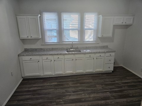 A kitchen with white cabinets and a granite countertop.