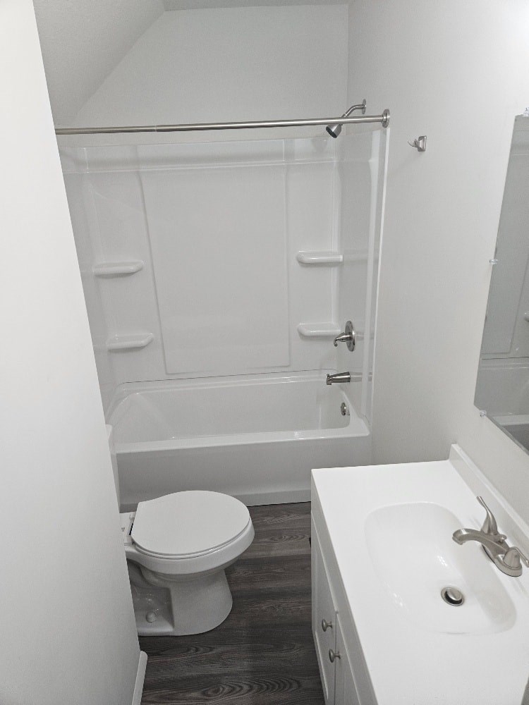 A white toilet sits next to a white sink in a small bathroom.