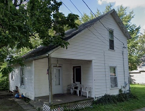 a white house with a porch and a table and chairs