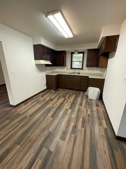 an empty kitchen with wood flooring in a new home