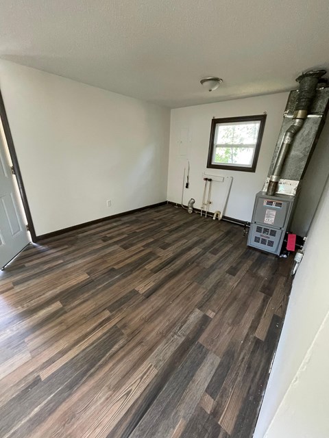 the living room has hardwood floors and a white wall and a window and a