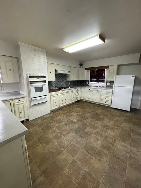 A kitchen with white cabinets and a tile floor.