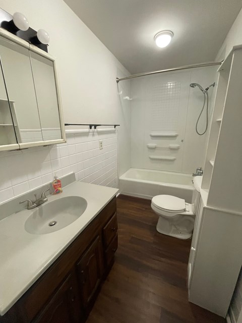 A white sink with a brown counter top and a white toilet in a bathroom.