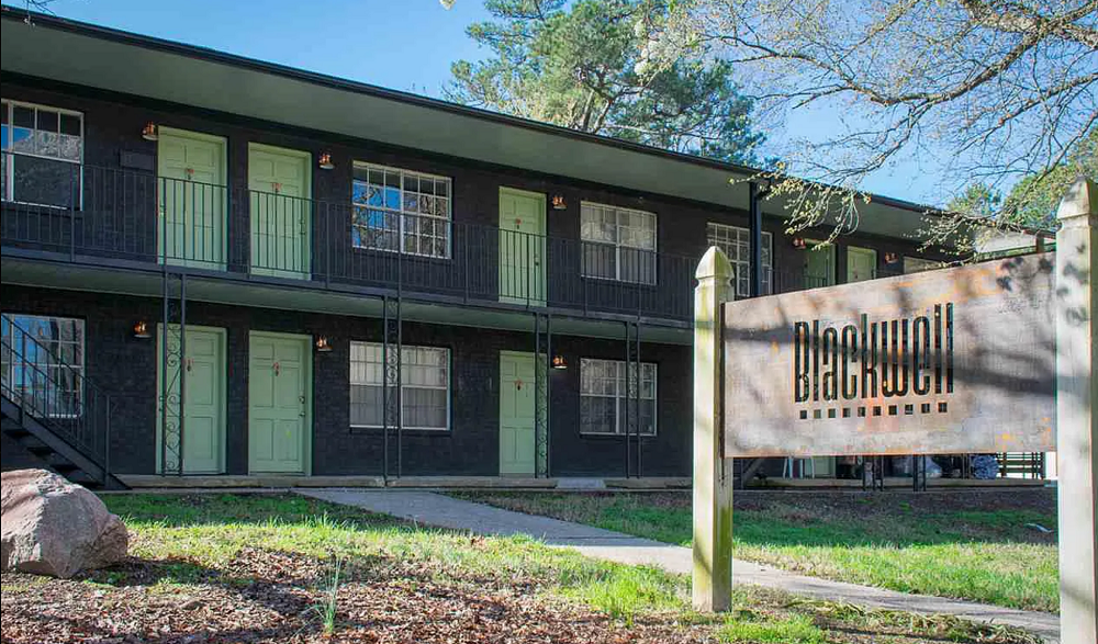 a building with green doors and a sign in front of it