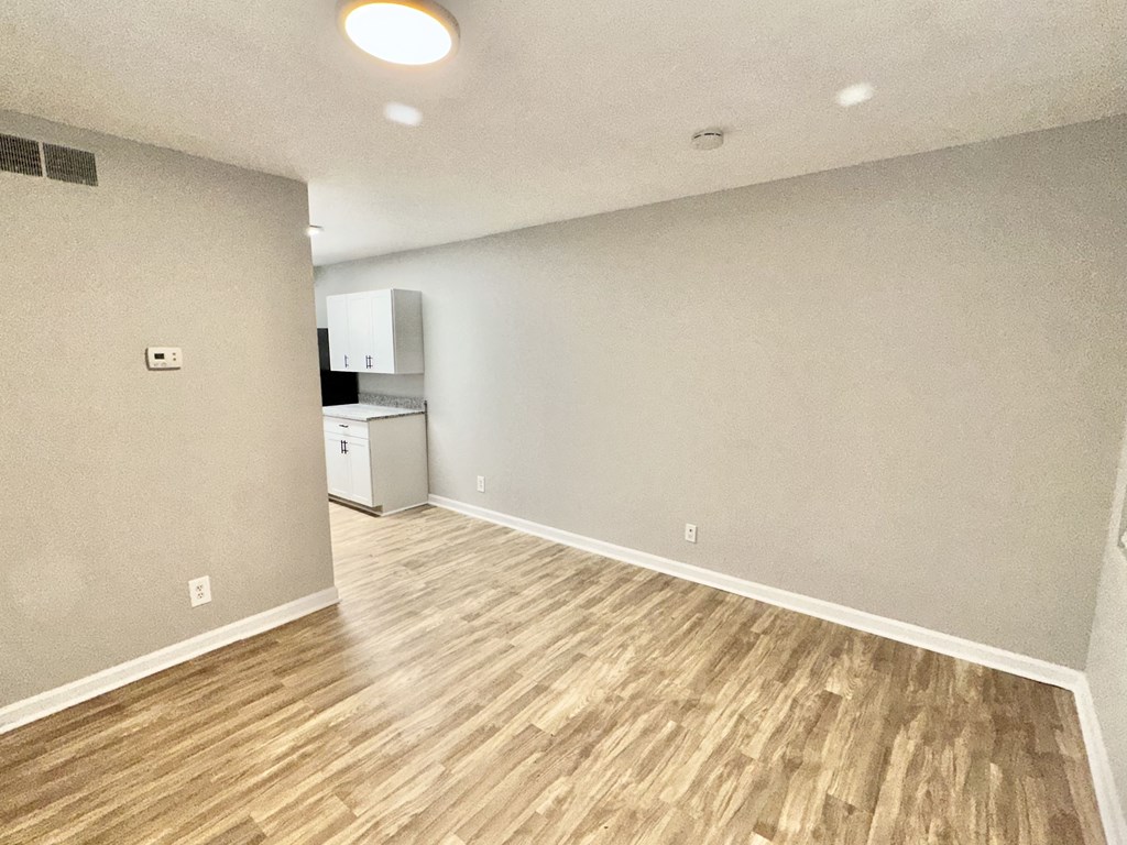 the living room and kitchen of an empty house with wood flooring