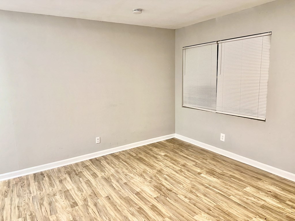 an empty room with wood flooring and a window