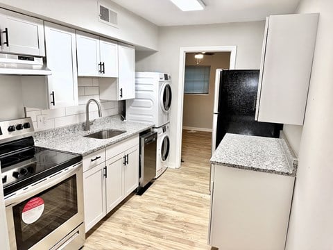 a kitchen with white cabinets and stainless steel appliances and a washer and dryer