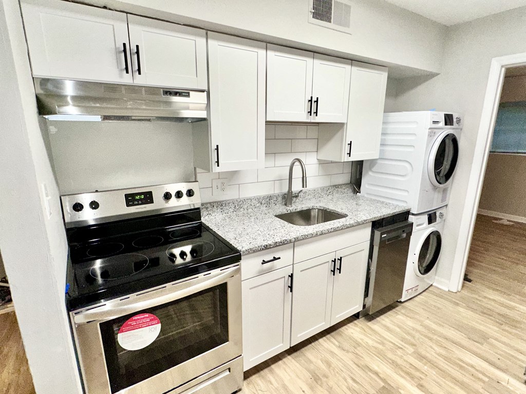 a kitchen with white cabinets and stainless steel appliances and a washing machine