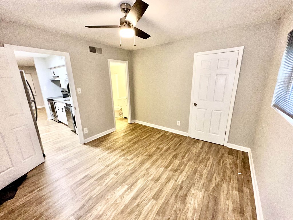 an empty living room with a wooden floor and a ceiling fan