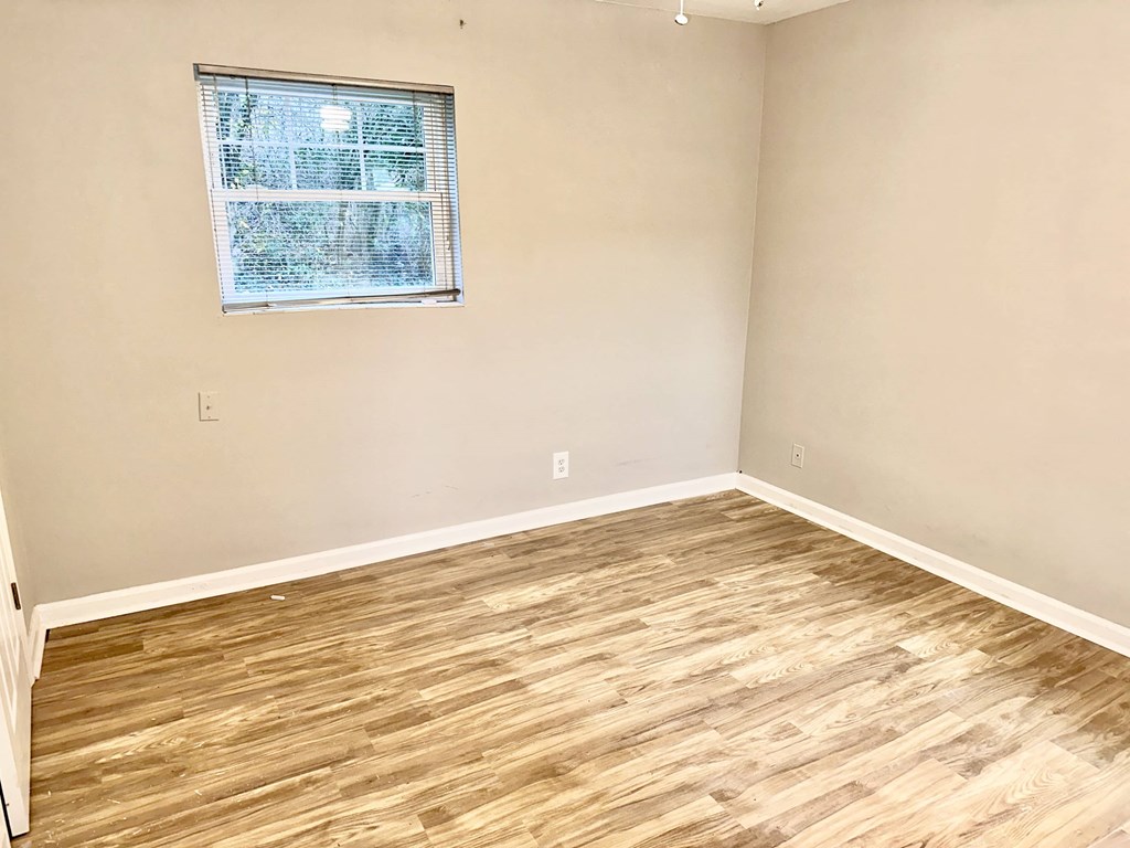 an empty room with wood flooring and a window