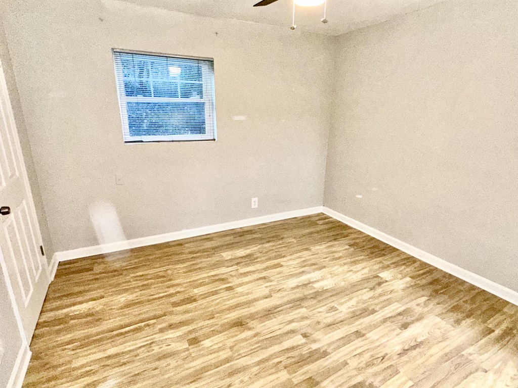 an empty room with wood floors and a window