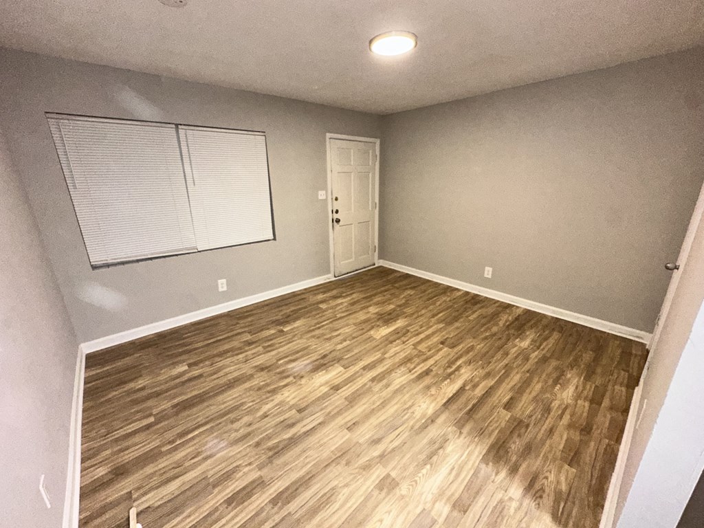 a living room with a hard wood floor and a white door