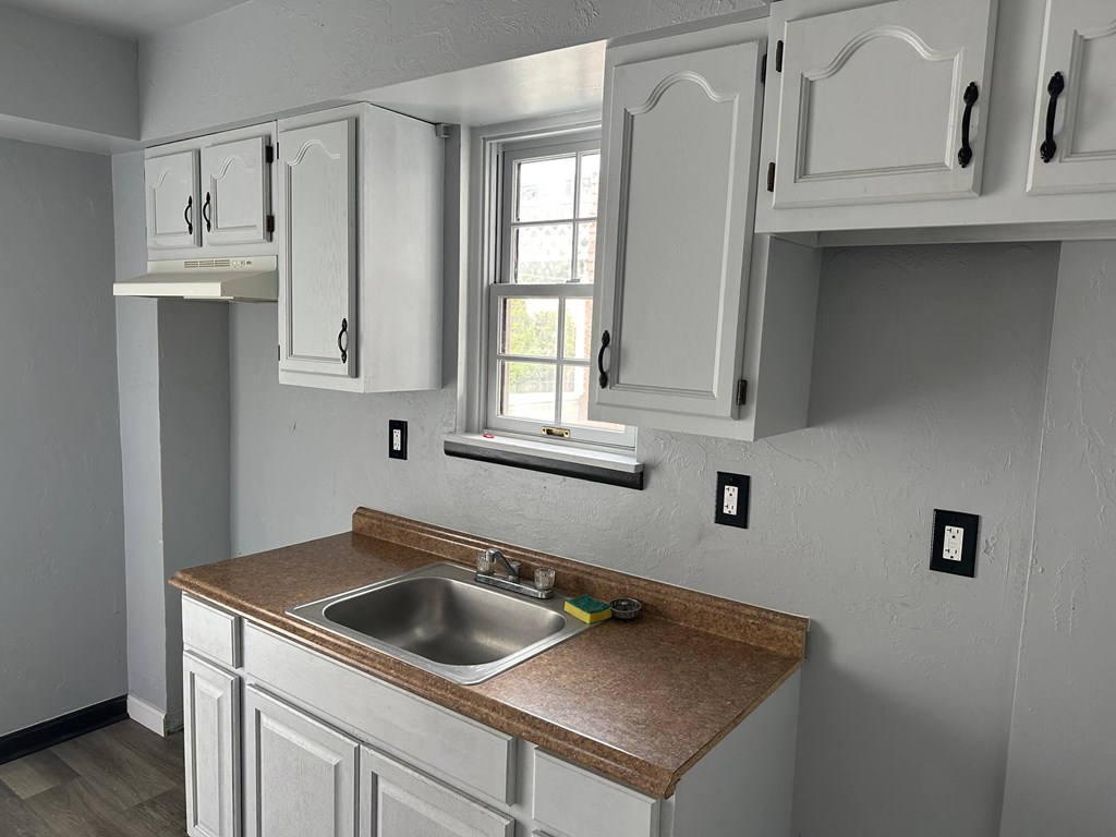 a kitchen with white cabinets and a sink and a window