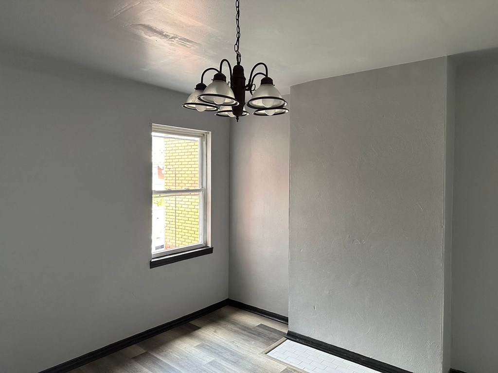 an empty room with a window and a chandelier