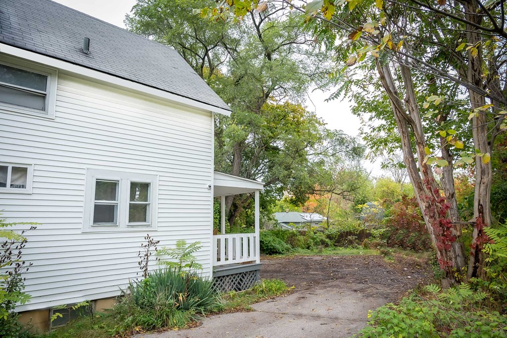 the side of a white house with a pathway next to it