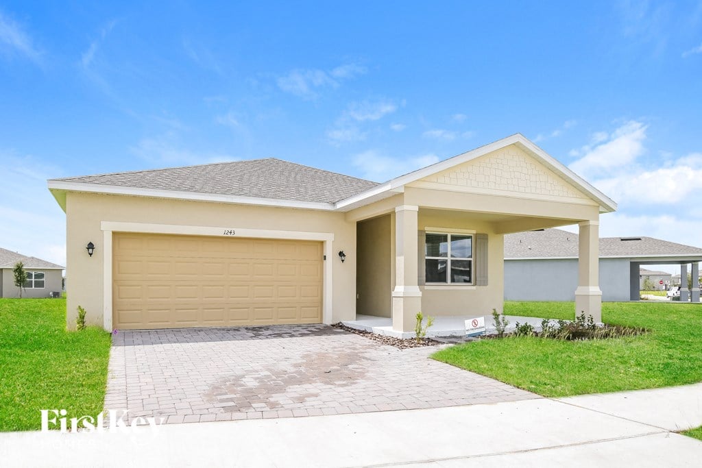 a beige house with a garage door and a driveway