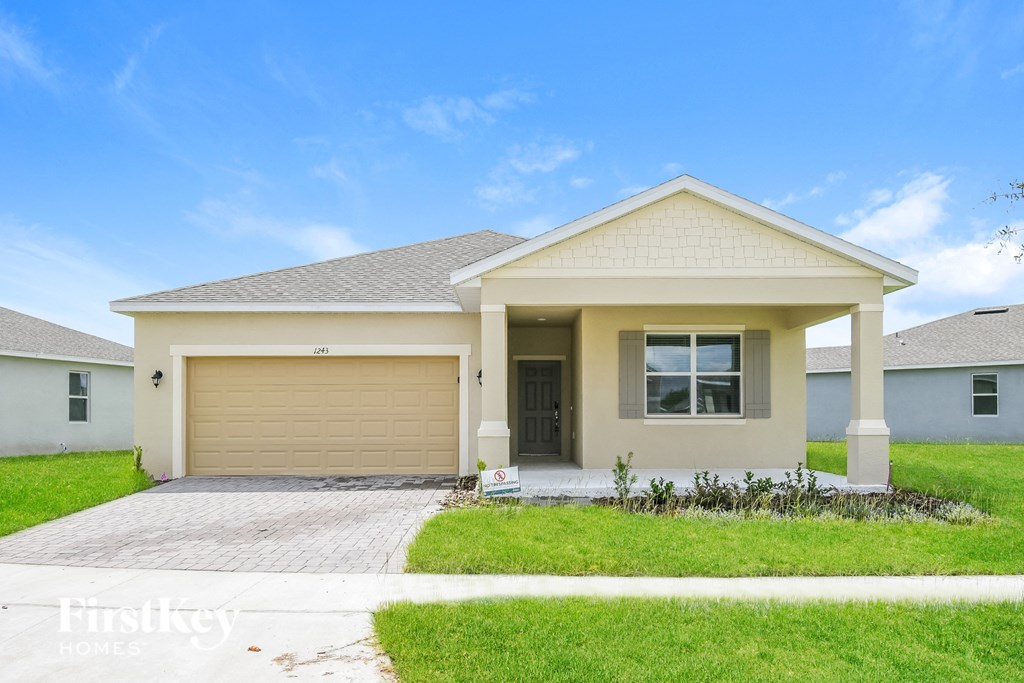 a beige house with a garage door and a lawn