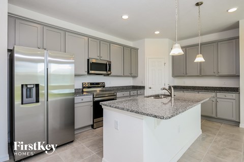 a white kitchen with stainless steel appliances and granite counter tops
