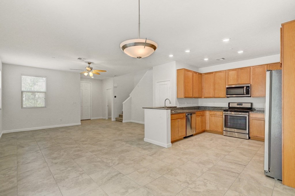 an empty kitchen with wooden cabinets and a stainless steel refrigerator