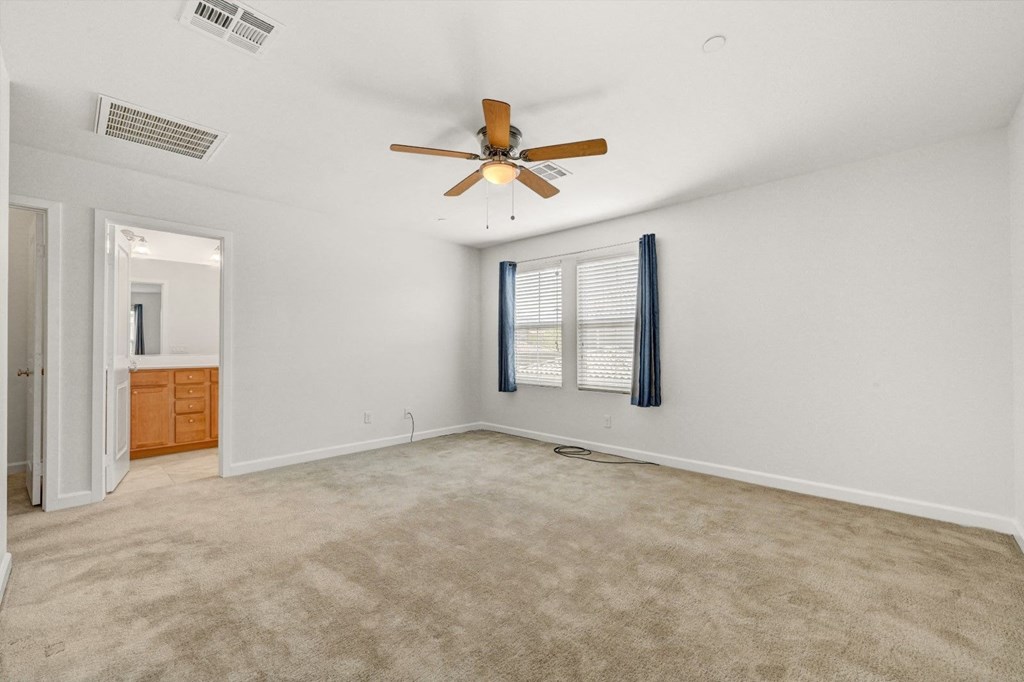 an empty living room with a ceiling fan and a window
