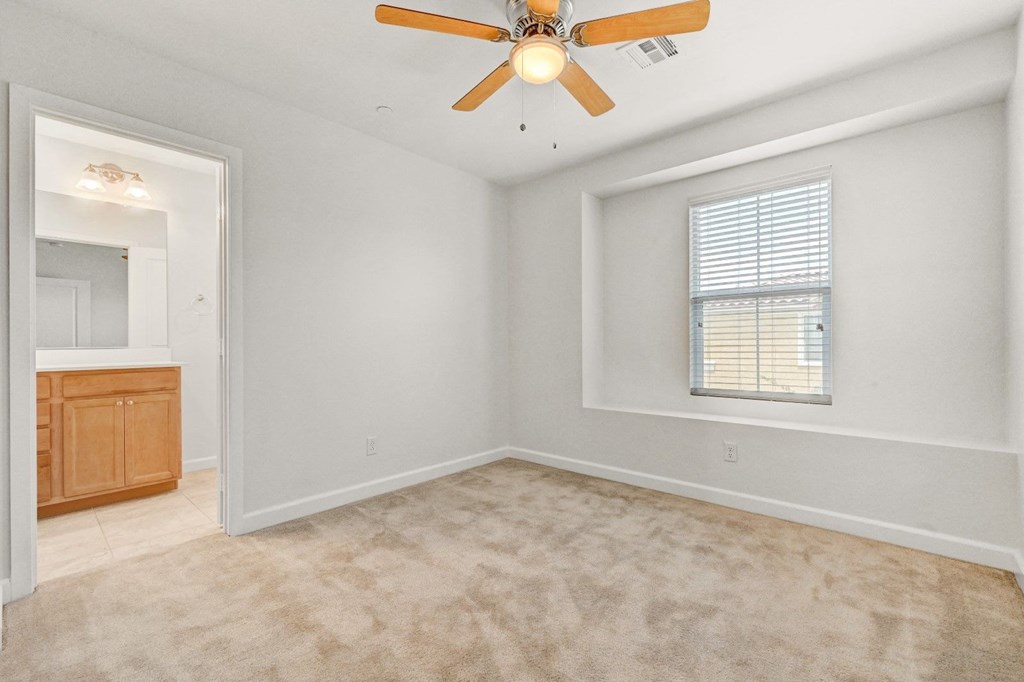 an empty living room with a ceiling fan and a window