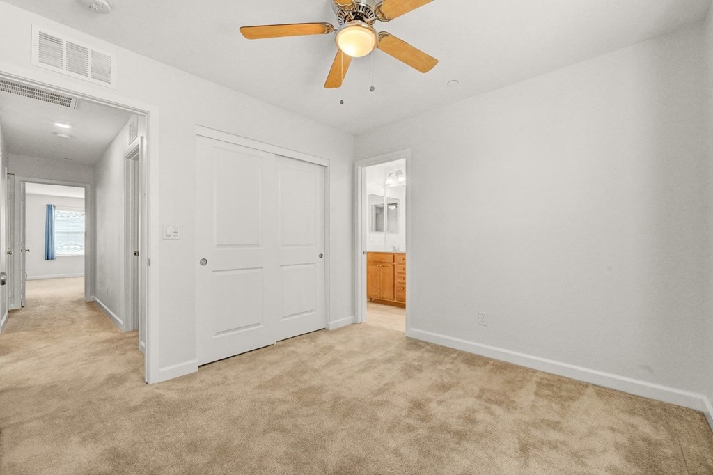 a living room with white walls and a ceiling fan
