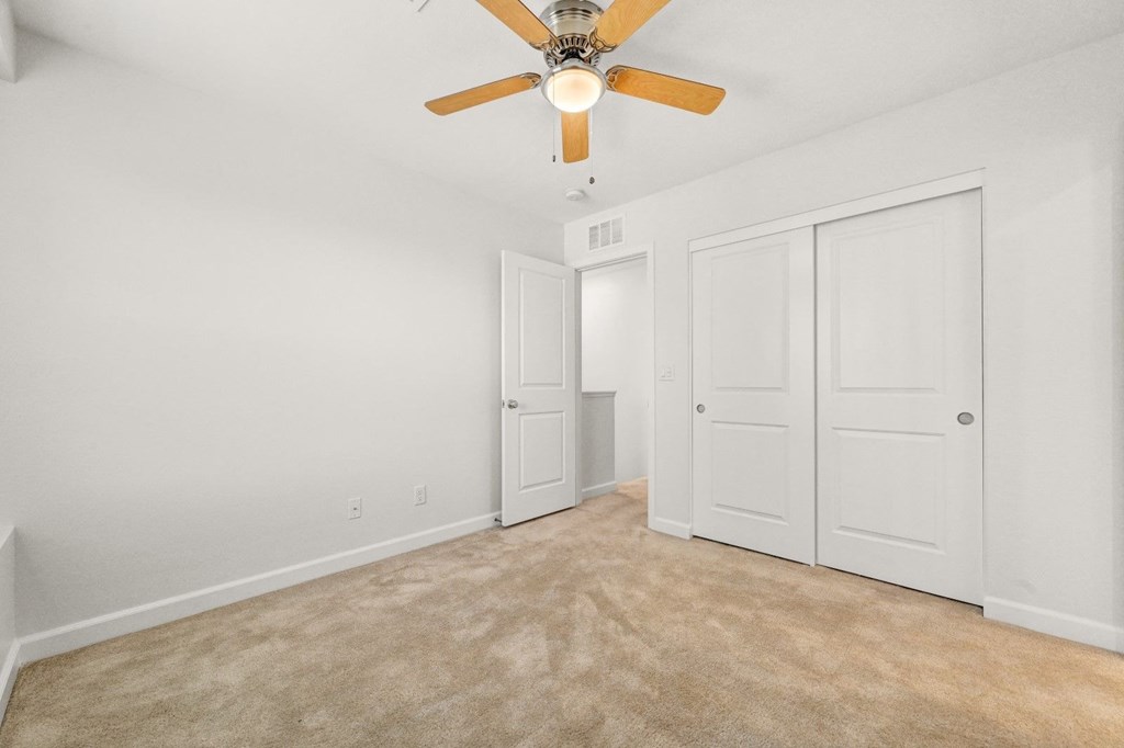 the living room of a home with white walls and a ceiling fan